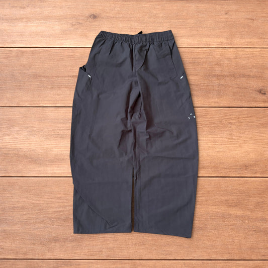 Grey baggy hiking trousers laid flat showing elasticated waistband and side pockets with branding