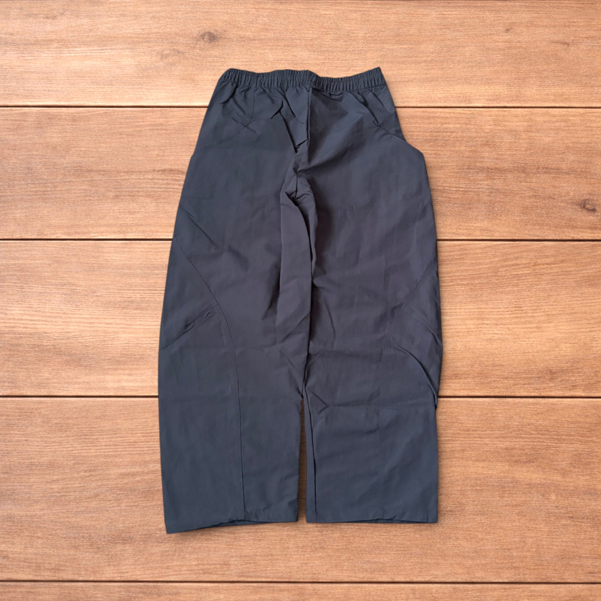 Grey baggy hiking trousers laid flat showing elasticated waistband and side pockets with branding