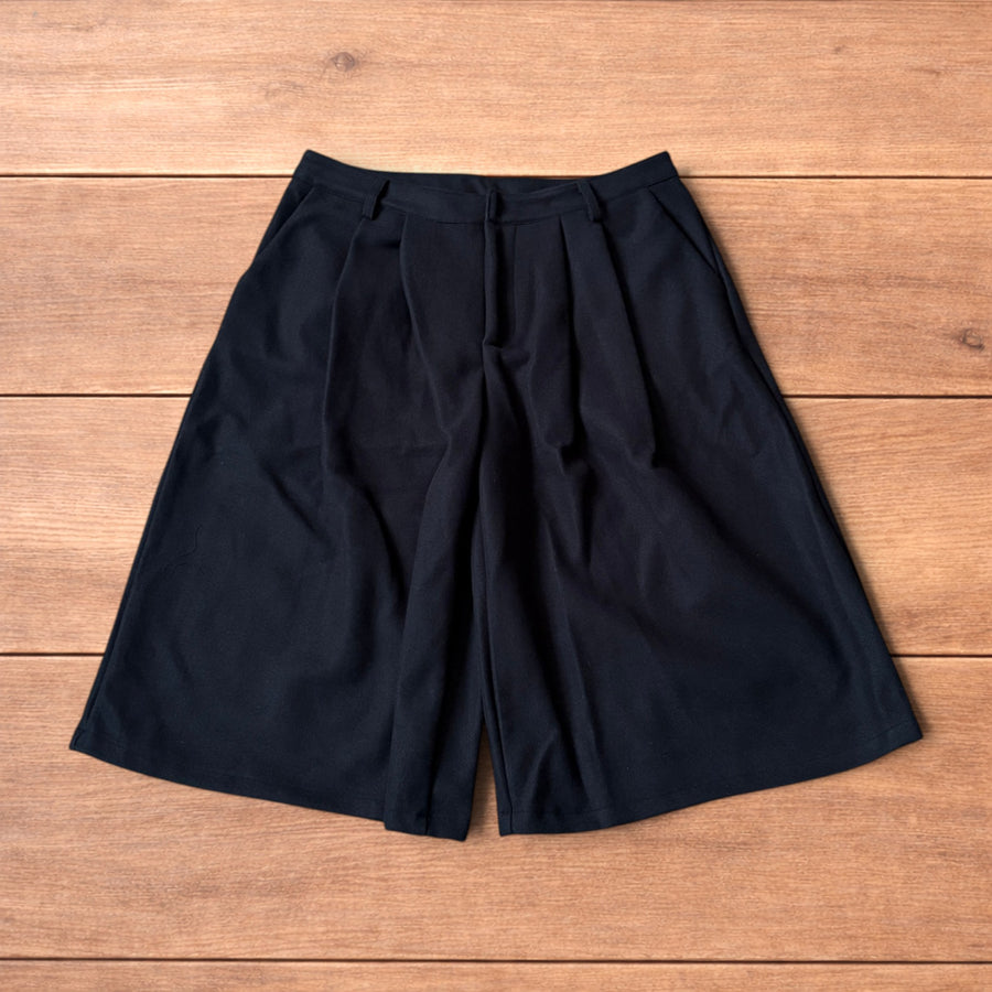 Black vintage style baggy wide leg long tailored wool shorts laid flat showing front, back, and waist details.