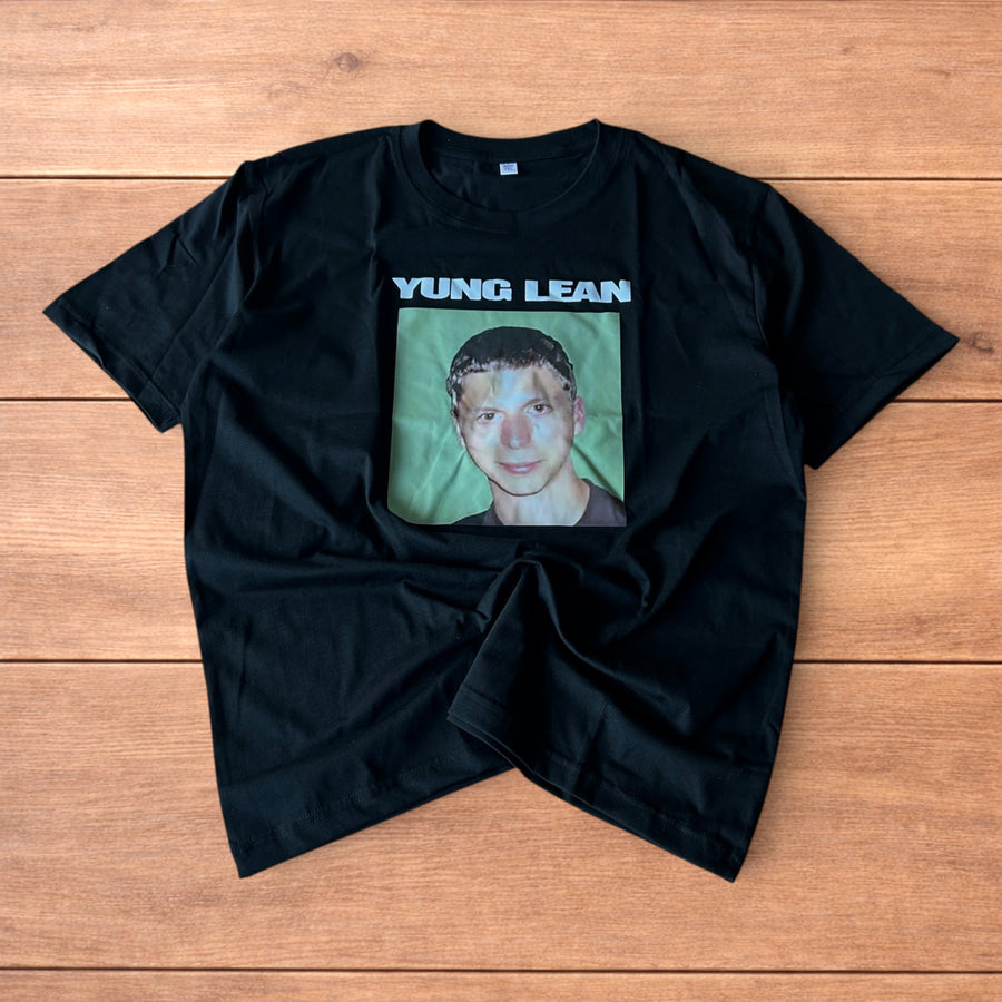 Black Yung Lean Superbad T-shirt with large front graphic print showing a portrait and text, laid flat on wooden surface
