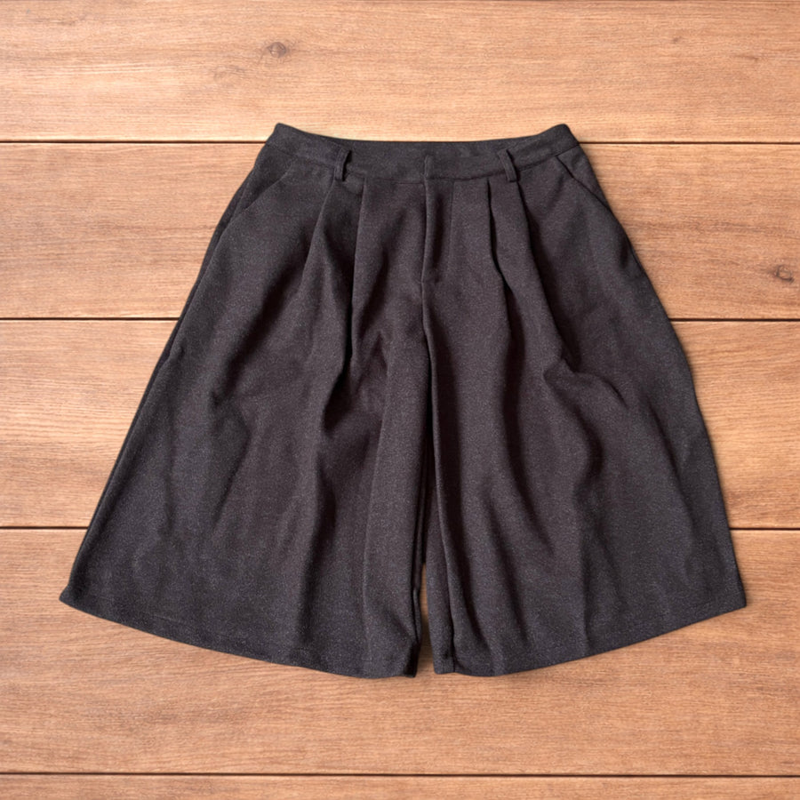 Brown vintage style baggy wide leg long tailored wool shorts laid flat on wood background showing front and back details.
