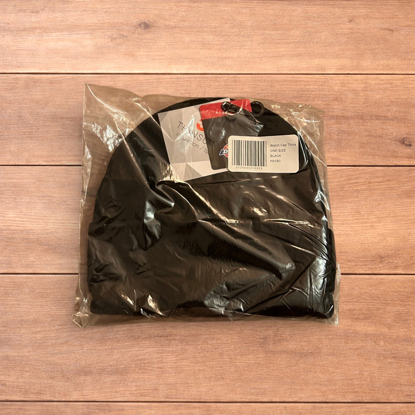 Black Dickies 3M Thinsulate beanie with patch logo on folded cuff, laid flat on wooden surface.