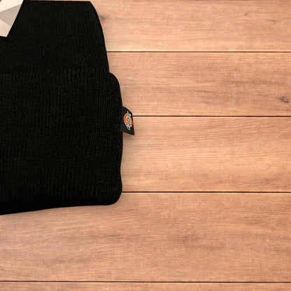 Black Dickies 3M Thinsulate beanie with patch logo on folded cuff, laid flat on wooden surface.