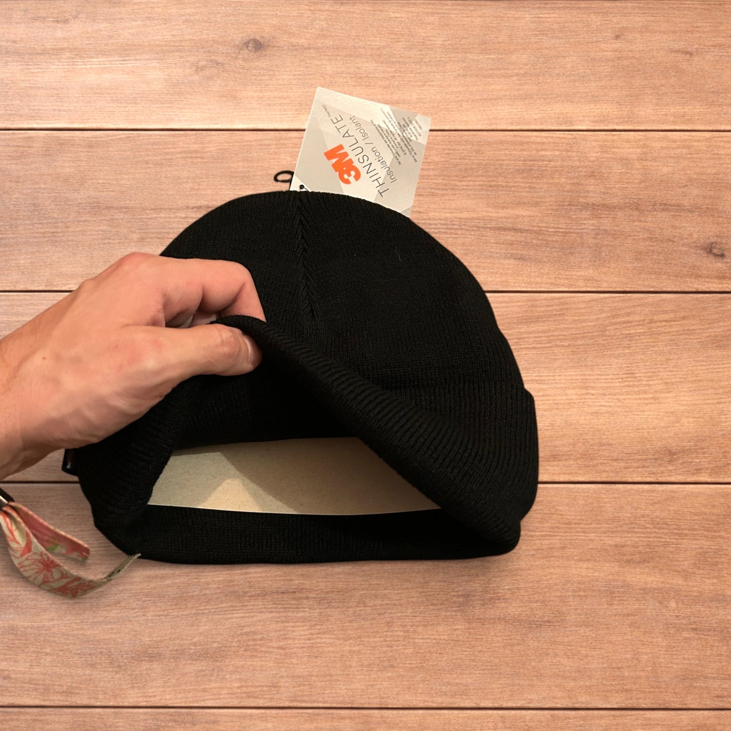 Black Dickies 3M Thinsulate beanie with patch logo on folded cuff, laid flat on wooden surface.