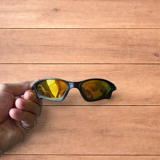 Insane polarised sunglasses in black with orange reflective lenses held against a wooden background.