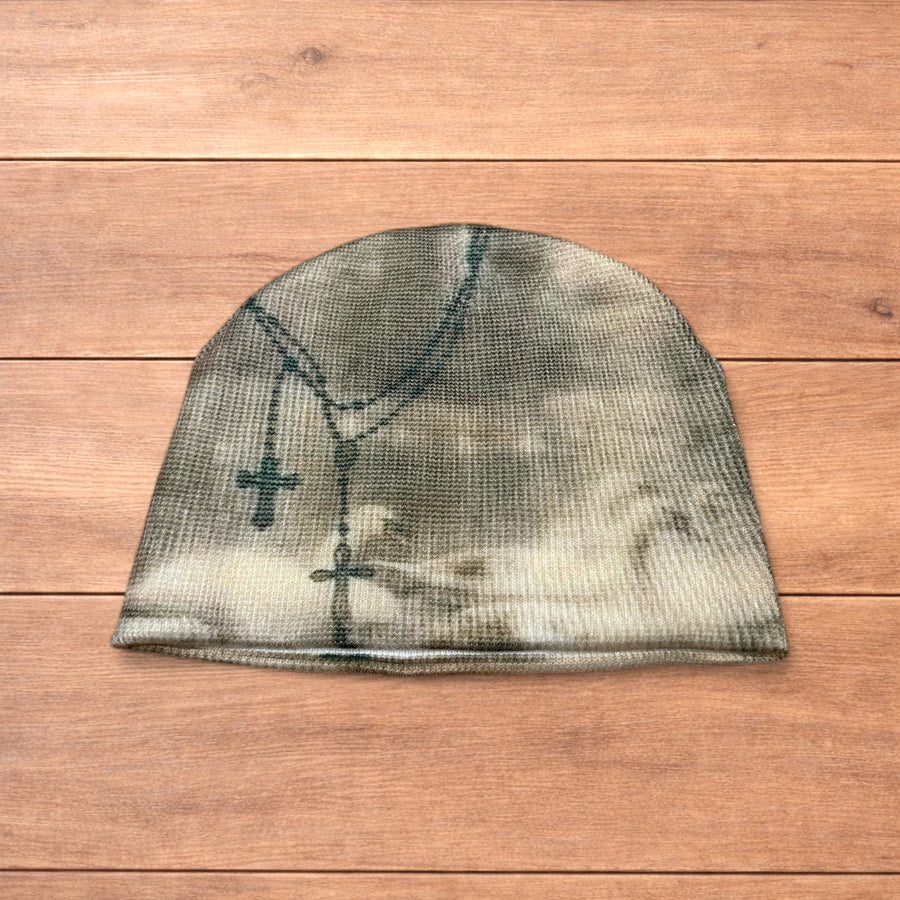 Cream beige Japanese vintage style beanie hat with graphic design showing crosses and script laid flat on wooden surface