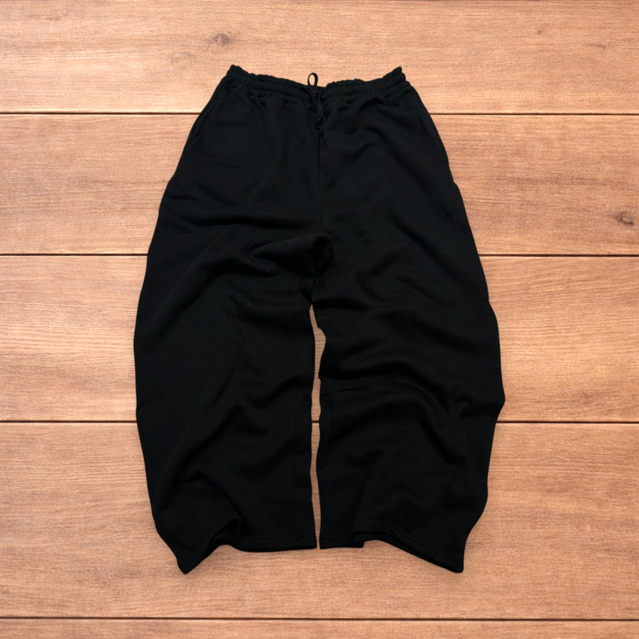 Black super baggy wide leg Korean joggers with elasticated drawstring waist and pockets laid flat on wooden surface.