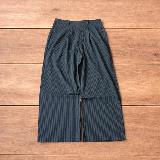 Charcoal grey vintage style pinstripe baggy wide leg tailored trousers laid flat on wooden background