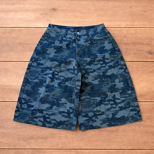 Super baggy wide leg cargo shorts jorts in muted army camo print laid flat on wooden floor