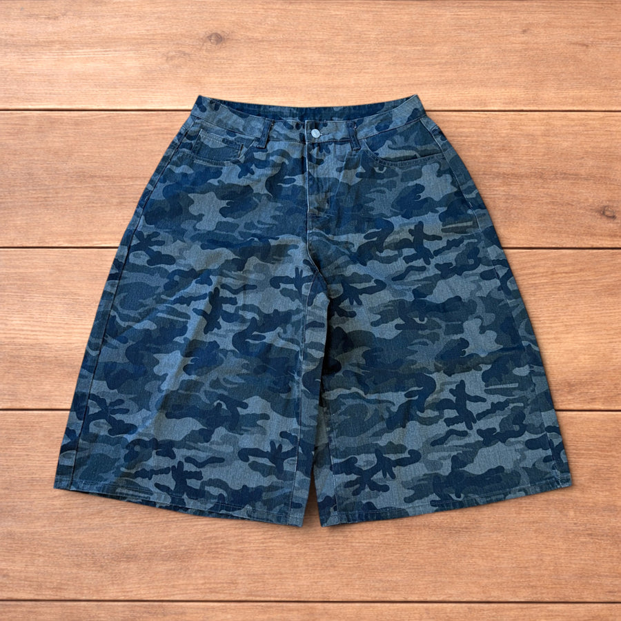 Super baggy wide leg cargo shorts jorts in muted army camo print laid flat on wooden floor
