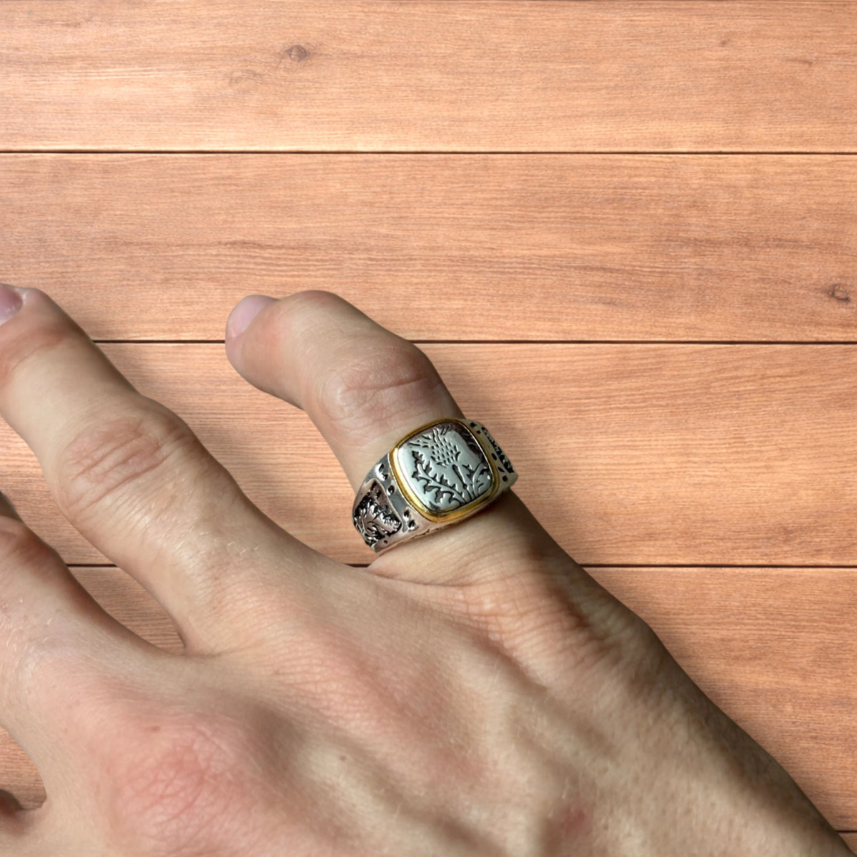 Silver chunky ring with Japanese nature design and gold trim worn on hand.
